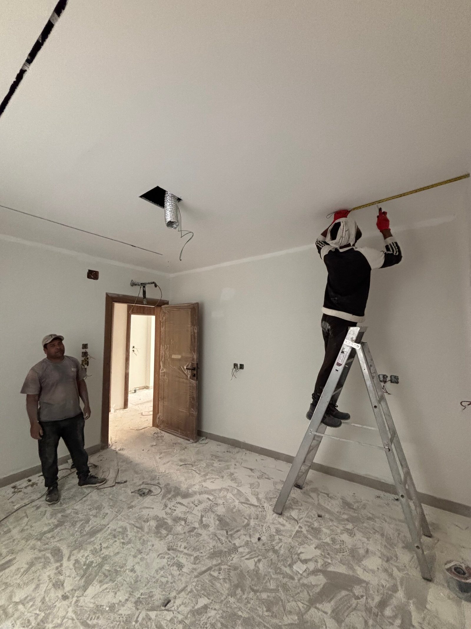 فني يقيس سقف جبس بورد داخل غرفة خلال مرحلة التشطيب النهائي