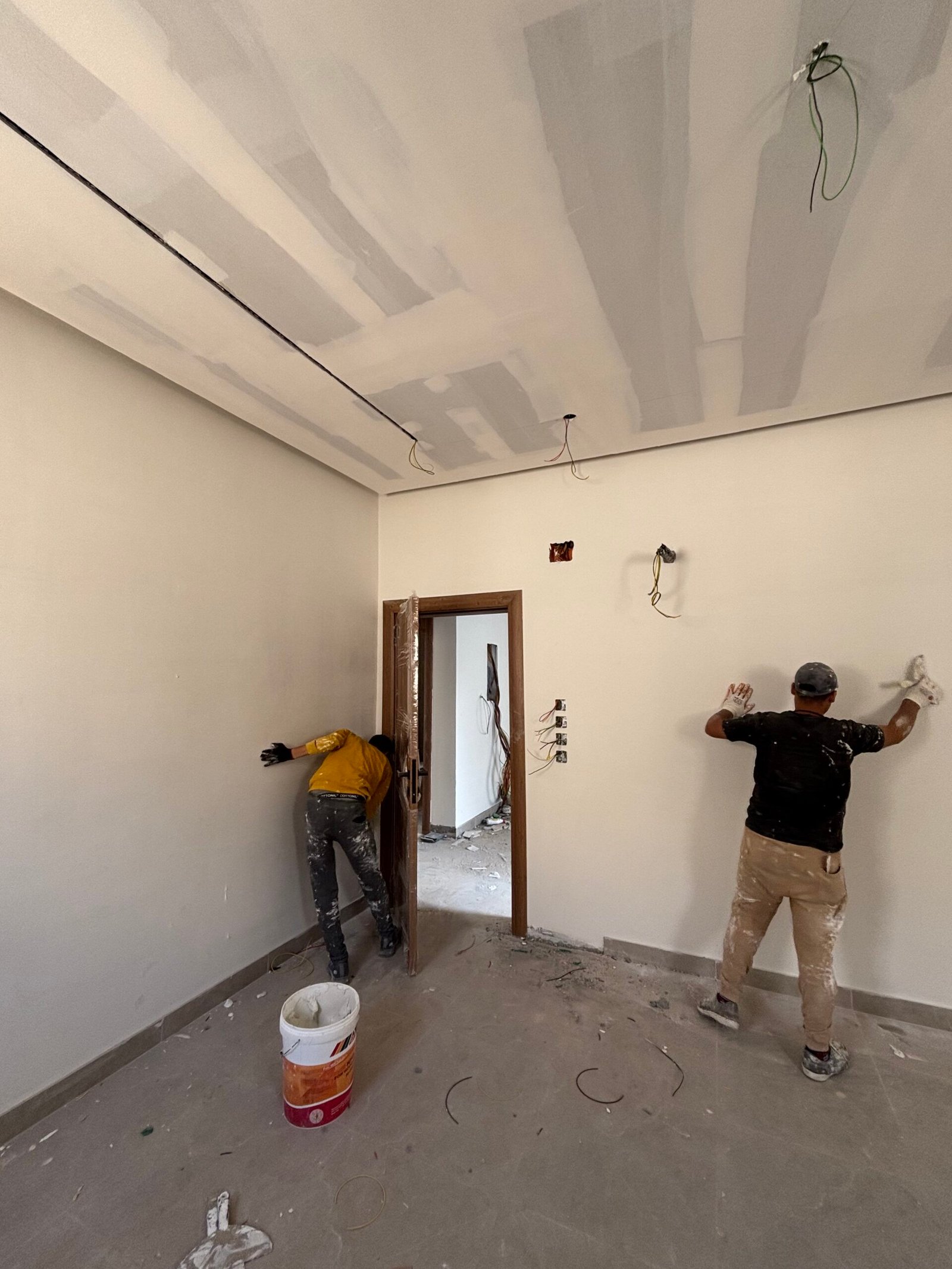 الجبس بورد في تبوك عمال ينفذون أعمال جبس بورد داخل غرفة سكنية في مرحلة التشطيب الداخلي